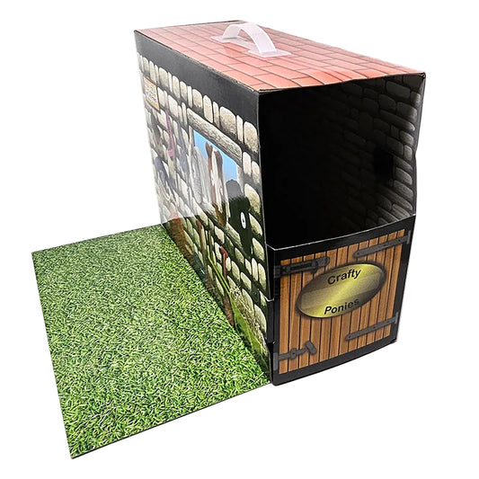 A cardboard stall and trailer box designed to look like a pony stall, featuring a black door with a name plate, a brown wooden structure, and a green grass-like floor.